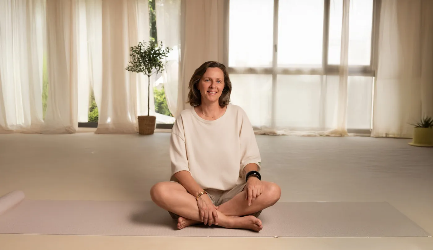 Lise Dehaye assise en tailleur sur un tapis, dans une salle lumineuse