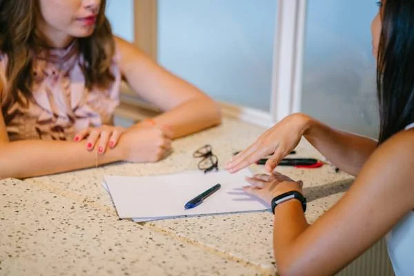 Mains posées sur une table pendant un échange avec la praticienne